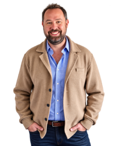 Dan Hardee smiling in a tan cardigan and blue shirt